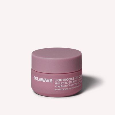 Un tarro rosa de Solawave LightBoost Eye Cream se centra sobre un fondo neutro, destacando su tecnología LightBoost y su fórmula con colágeno vegano para amplificar y reafirmar las propiedades para elevar su rutina de cuidado de la piel.